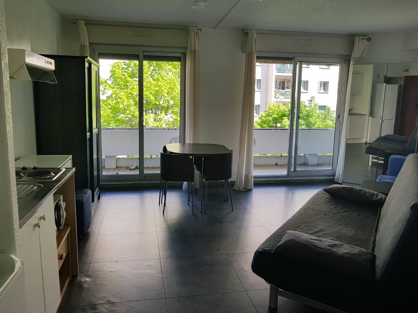 Grande pièce à vivre lumineuse d'un studio meublé, avec kitchenette et accès terrasse